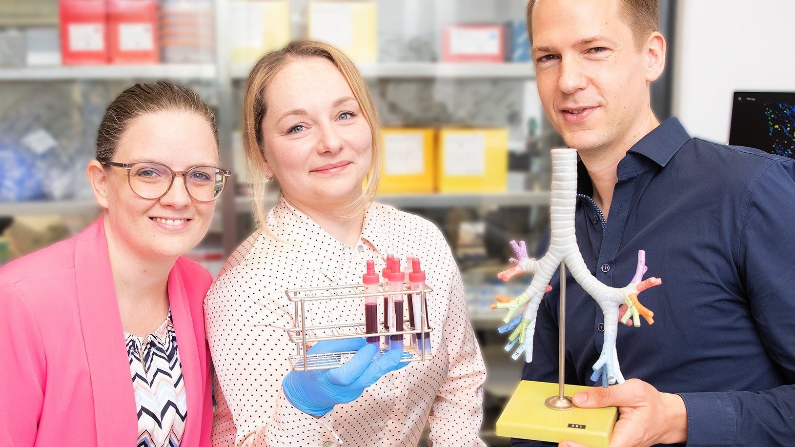 PD Dr. Lavinia Neubert, Doktorandin Edith Katharina Schwarz und PD Dr. Jan-Christopher Kamp stehen in einem Labor und halten ein Lungenmodell und Blutproben in den Händen.