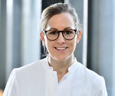 Porträtbild von Anna-Lena Weber, die einen weißen Arzt-Kittel trägt. 