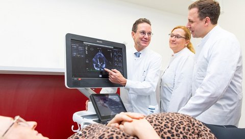Professor Dr Johann Bauersachs (left), private lecturer Dr Melanie Ricke-Hoch (centre) and private lecturer Dr Tobias Pfeffer look at the heart ultrasound image of a pregnant woman.