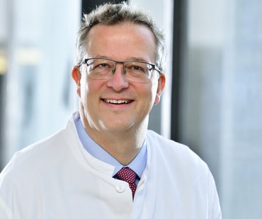 Portärtbild von Christoph Terkamp, der einen weißen Arztkittel trägt. 