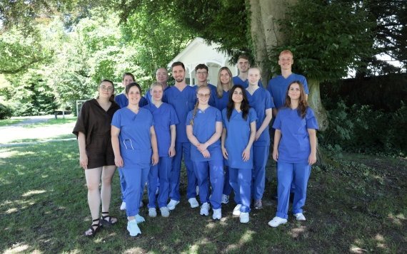 Copyright: Franziskus Hospital Bielefeld Eine Gruppe von Personen in blauen Kasacks steht in einem Garten.