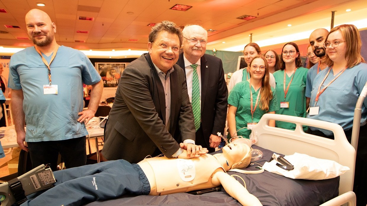 Gesundheitsminister Philippi und Prof. Manns stehen beim MHH-Event im aufhof an einem Patientenbett und reanimieren eine Puppe. 