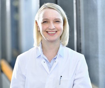 Porträtbild von Katja Deterding, die einen weißen Arztkittel trägt.