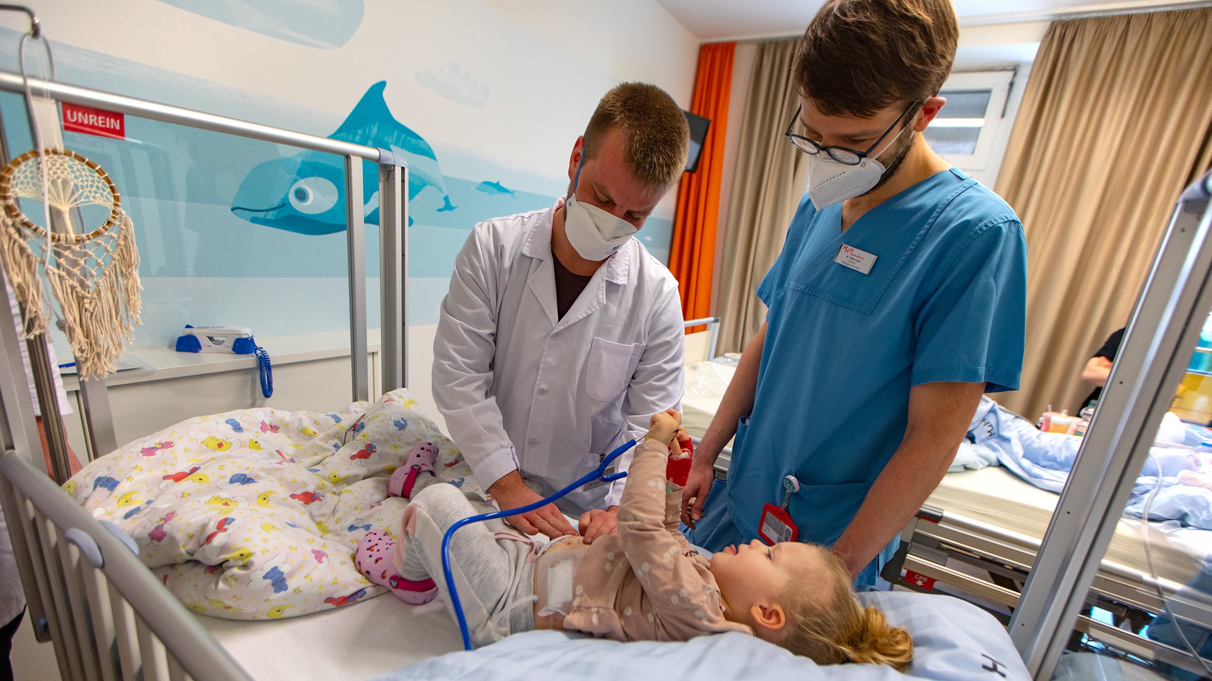 MHH-Student Niklas Oetzmann steht am Bett einer Patientin in der Kinderklinik und untersucht die Bauchdecke ihre Bauchdecke.