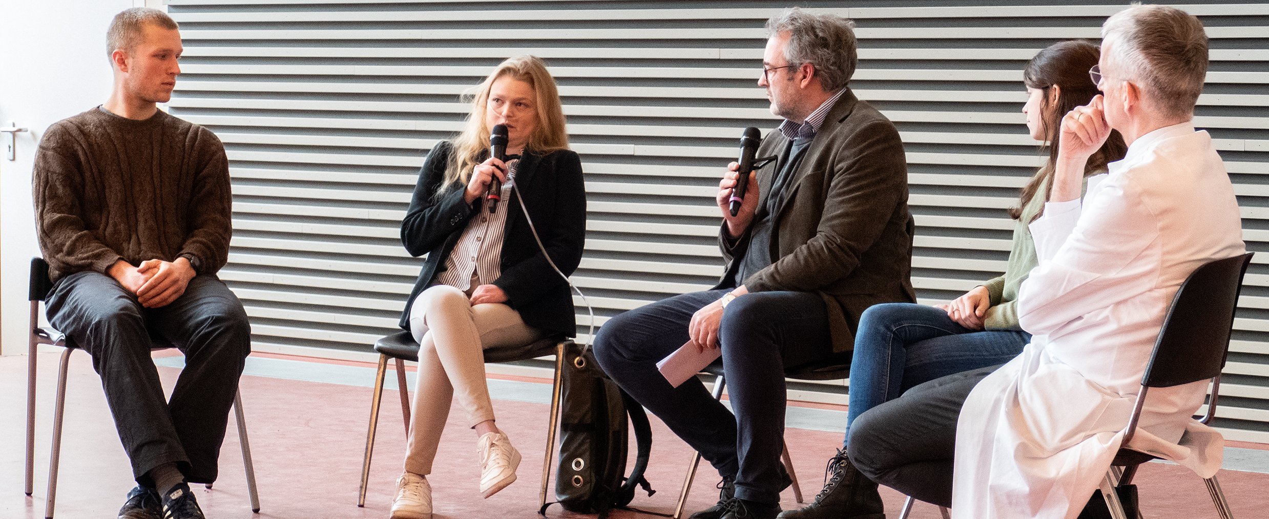 (v. l.) Malte Storsberg, India Heilmann, Prof. Dr. Christian Mühlfeld, Lina Rosenboom und Prof. Dr. Frank Lammert sitzen auf dem Podium eines Hörsaals. 