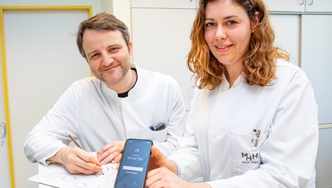 A man and a woman in doctor's coats demonstrate two medical test procedures.