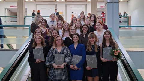 Die Absolventinnen stehen für ein Gruppenfoto auf einer Treppe zusammen. 