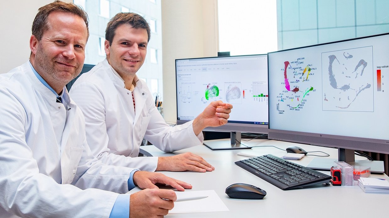 Clinic director Professor Schmidt-Ott (left) and his senior physician Dr Christian Hinze sit at a table with two PC monitors and a keyboard.