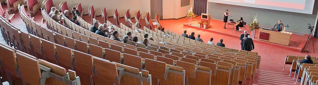 Blick in den Hörsaal F der MHH, in dem einige Menschen auf den Stuhlbänken sitzen. 