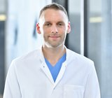 Copyright: Tom Figiel Porträtbild von Christoph Beier, der einen weißen Arztkittel trägt.
