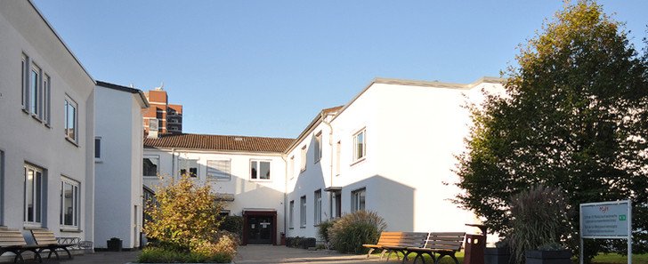 Es ist die MTRA-Schule zu sehen. Weißes Gebäude mit Innenhof.