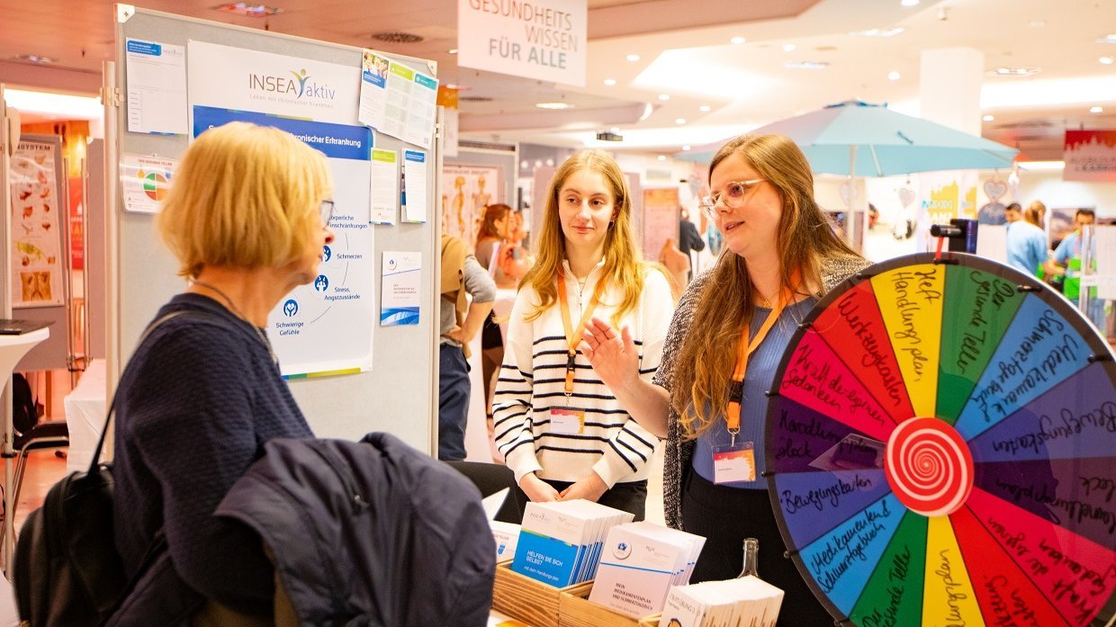 A woman talks to two other women at the INSEA stand. 