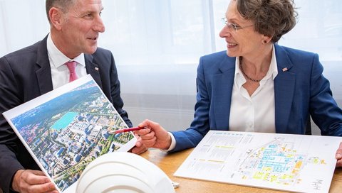 Michael Raasch and MHH Vice President Martina Saurin sit next to each other at a table with construction plans in front of them.