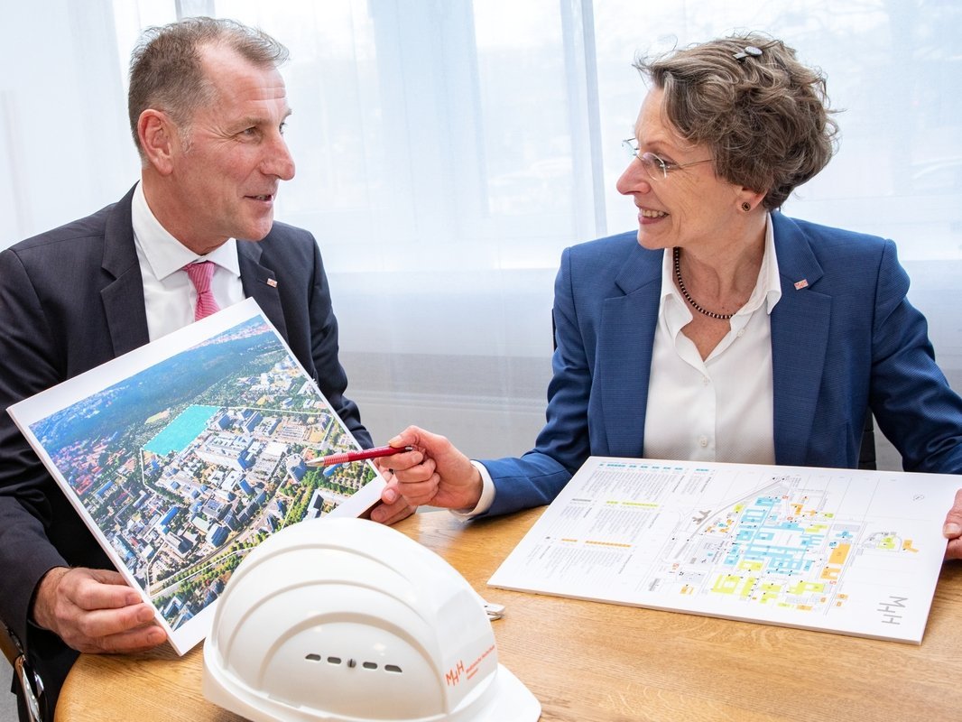 Michael Raasch and MHH Vice President Martina Saurin sit next to each other at a table with construction plans in front of them.