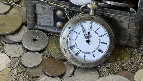 Eine Taschenuhr ist an eine kleine Truhe gelehnt. In und vor der Truhe liegen verschiedene Münzen verstreut.