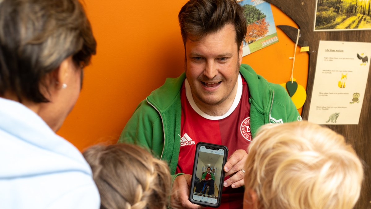 Sven Kamin zeigt den Kindern das fertige Video auf seinem Handy.