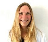 Porträtbild von Johanna Doll-Lee, die einen weißen Arztkittel und ihre blonden langen Haare offen trägt.