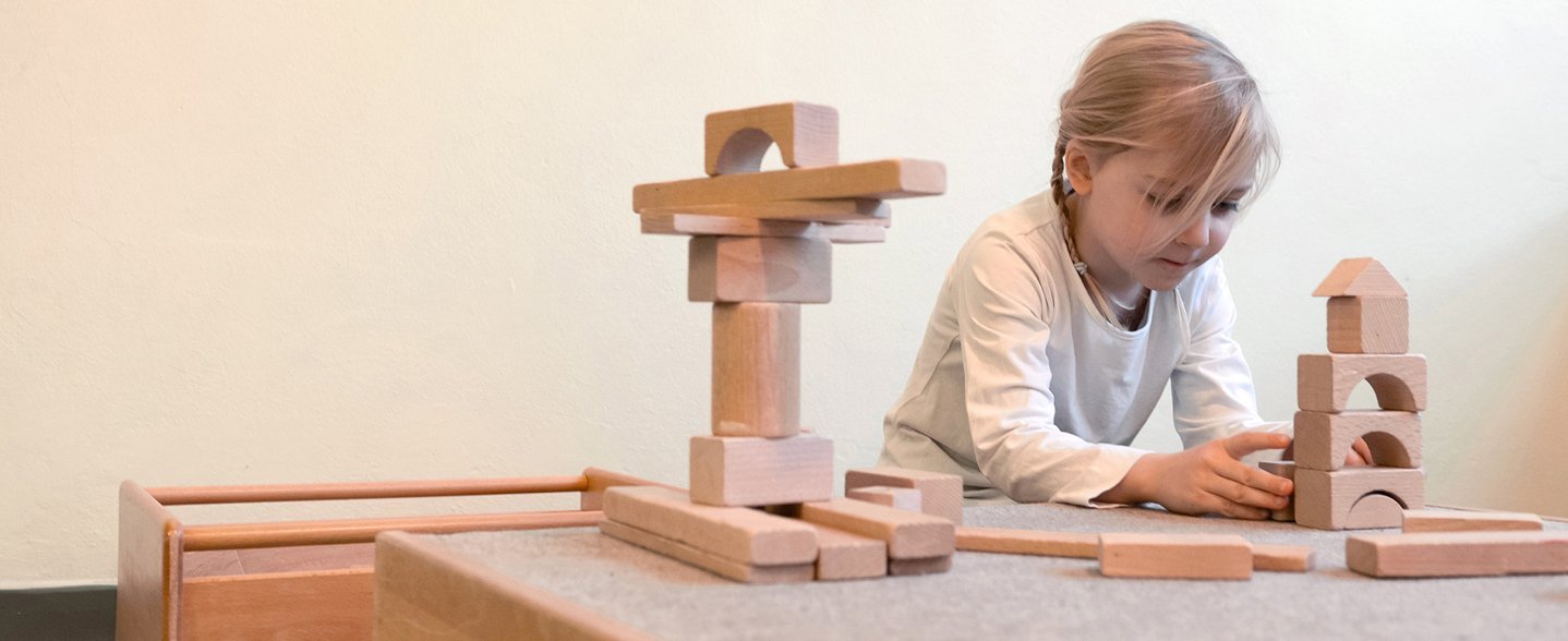 Ein kleines Mädchen spielt mit Bauklötzen.