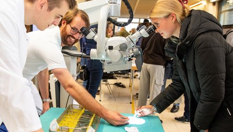 Eine junge Frau schaut durch ein Mikroskop. 