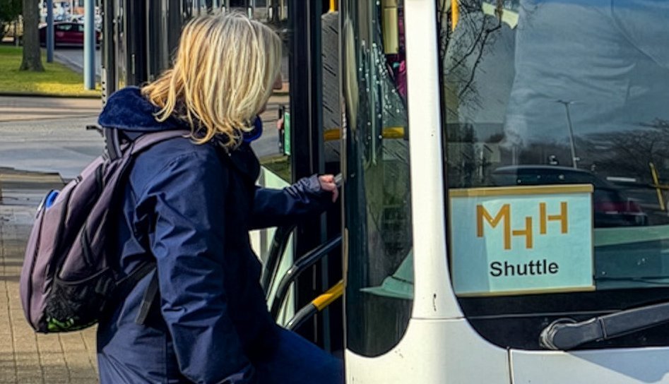 eine Frau steigt in einen Bus, in dem ein Zettel mit der Aufschrift "MHH Shuttle" liegt