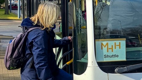 eine Frau steigt in einen Bus, in dem ein Zettel mit der Aufschrift "MHH Shuttle" liegt