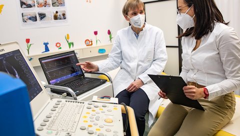 Professorin Dr. Dr. Anette Melk (links) diskutiert mit Dr. Rizky Sugianto über einen auf dem Bildschirm abgebildeten Pulswellenbefund.