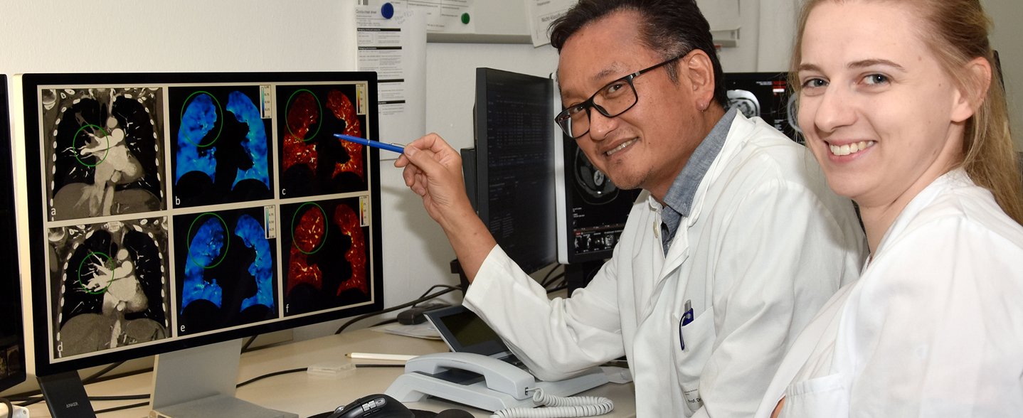 Das Foto zeigt einen Arzt und eine Ärztin, die am Bildschirm die CT-Aufnahmen einer Lunge betrachten. Struktur, Belüftung und Durchblutung des Organs sind jeweils in andern Farben dargestellt.  