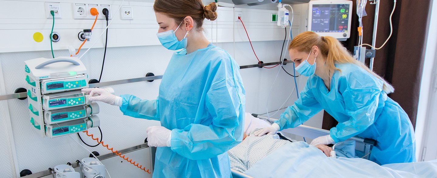 zwei weibliche Pflegekräfte stehen an einem Krankenbett