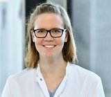 Porträtbild von Sabrina Welland, die einen weißen Arztkittel trägt. 