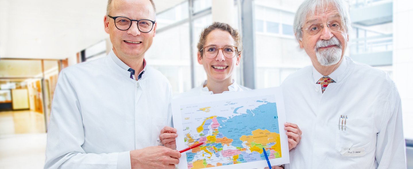 Professor Dr. Heiner Wedemeyer, Dr. Lisa Sandmann und Professor Dr. Michael Gebel zeigen auf einer Landkarte Deutschland und Usbekistan. Copyright: Karin Kaiser / MHH