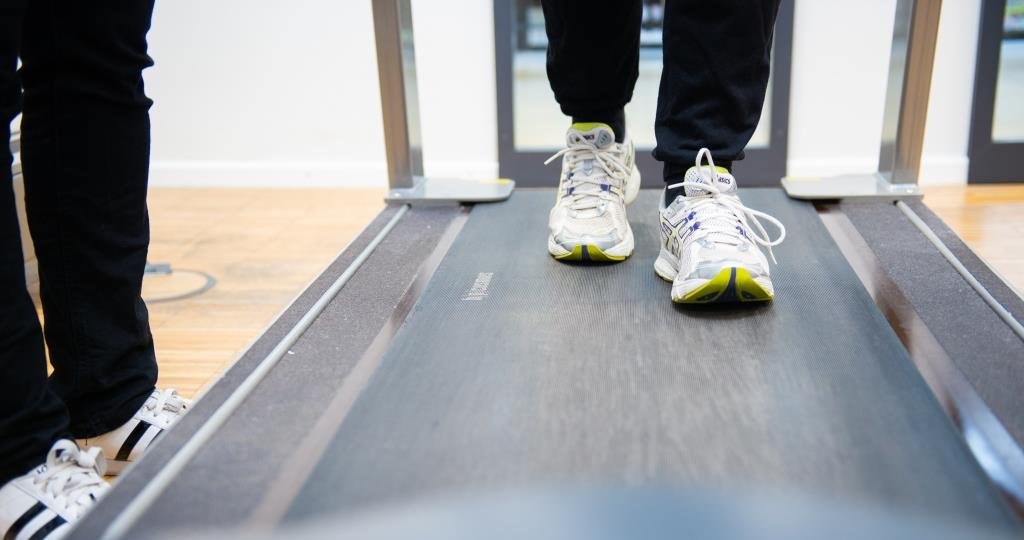 Eine Person mit Sportschuhen auf einem Laufband. Zu sehen sind nur die Füße.