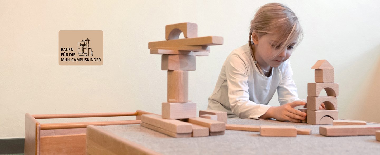 Ein Mädchen baut mit Holzklötzen einen Turm.