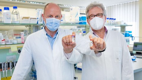 Professor Behrens (left) and Professor Förster in the MHH Institute of Immunology with vaccine vials of the companies AstraZeneca and Biontech/Pfizer held crosswise. 