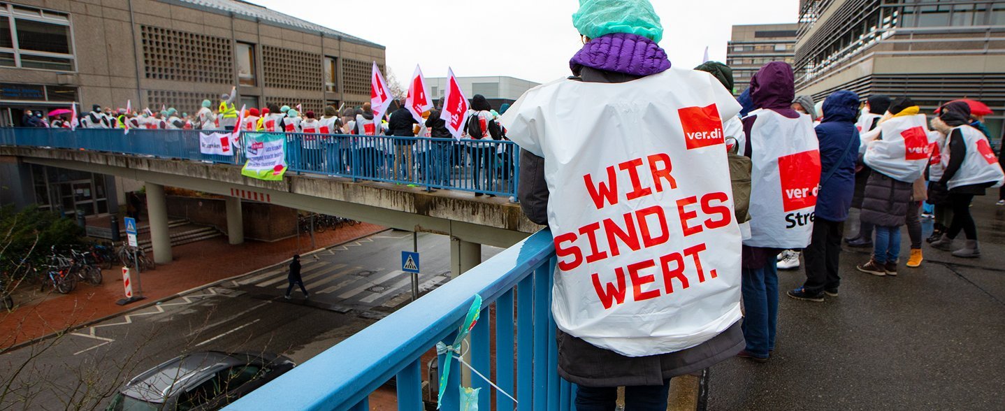 Archive image shows several striking employees standing on a high bridge on the MHH campus with Verdi flags.