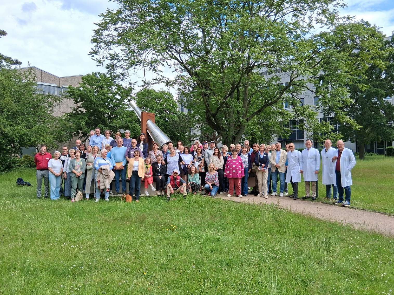 Eine große Gruppe aus Langzeit-Lebertransplantierten, Angehörigen und medizinischem Personal versammeln sich am DankeMal im Patientengarten der MHH – einem Ort des Gedenkens an die Organspenderinnen und Organspender.