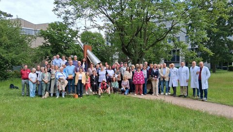 Eine große Gruppe aus Langzeit-Lebertransplantierten, Angehörigen und medizinischem Personal versammeln sich am DankeMal im Patientengarten der MHH – einem Ort des Gedenkens an die Organspenderinnen und Organspender.