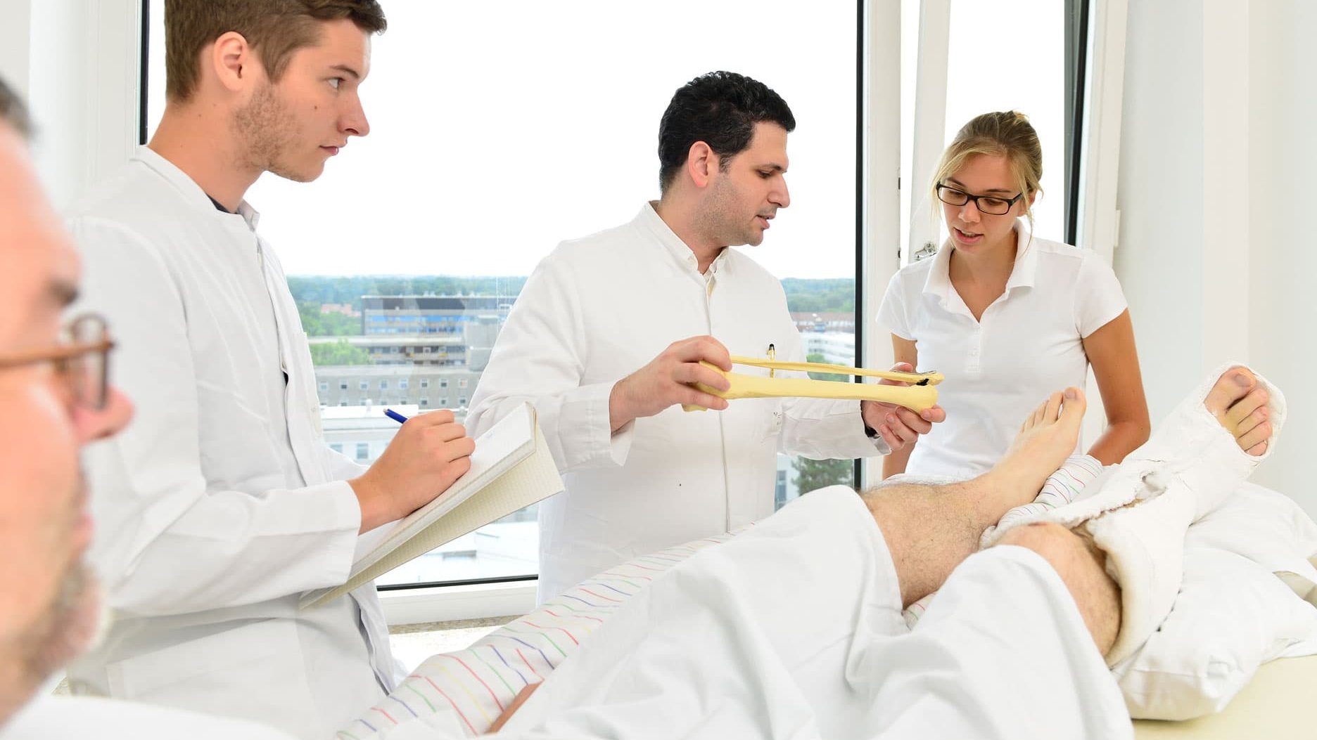 Eine Gruppe von Ärzten und Ärztinnen bei der Visite am Krankenbett