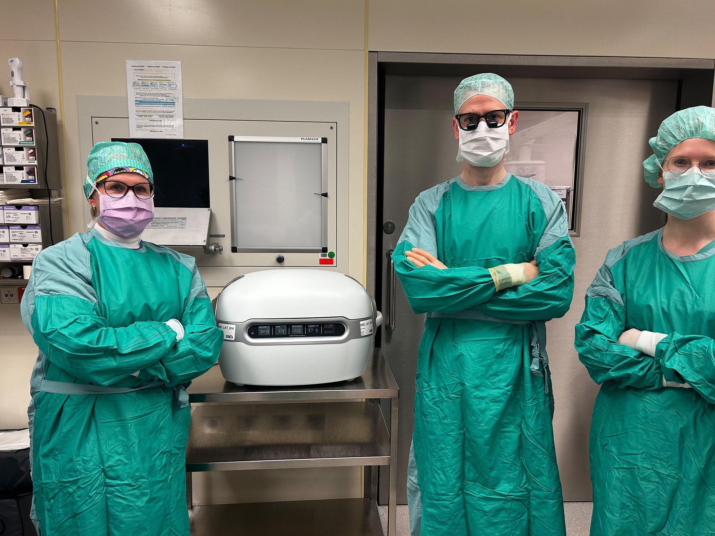 Männer und Fraun stehen in Kitel neben einer Maschine