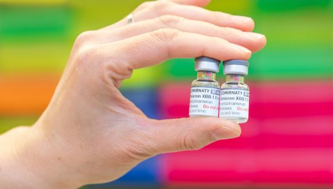 One hand holds two vials of coronavirus vaccine.