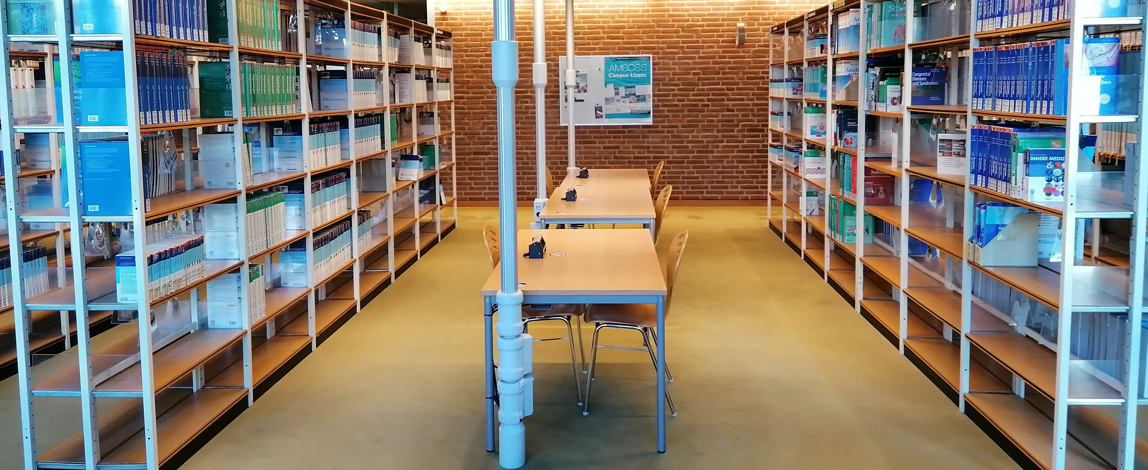 Lernplätze im unteren Lesesaal zwischen Regalen mit ausleihbaren Büchern