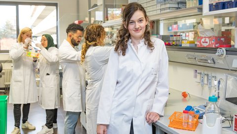 The young doctor Dr. Laura Hinze is standing in her laboratory with her working group