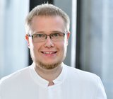 Porträtbild von Michael Dölle, der einen weißen Arztkittel trägt. 