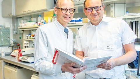 Professor Dr. Heiner Wedemeyer (links) und Professor Dr. Markus Cornberg stehen in einem Labor der Klinik für Gastroenterologie, Hepatologie, Infektiologie und Endokrinologie.