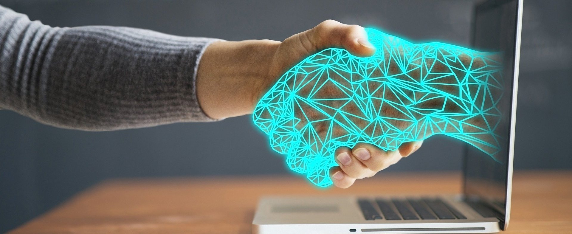 Technologische Hand ragt aus dem Laptop und reicht Teilnehmer die Hand