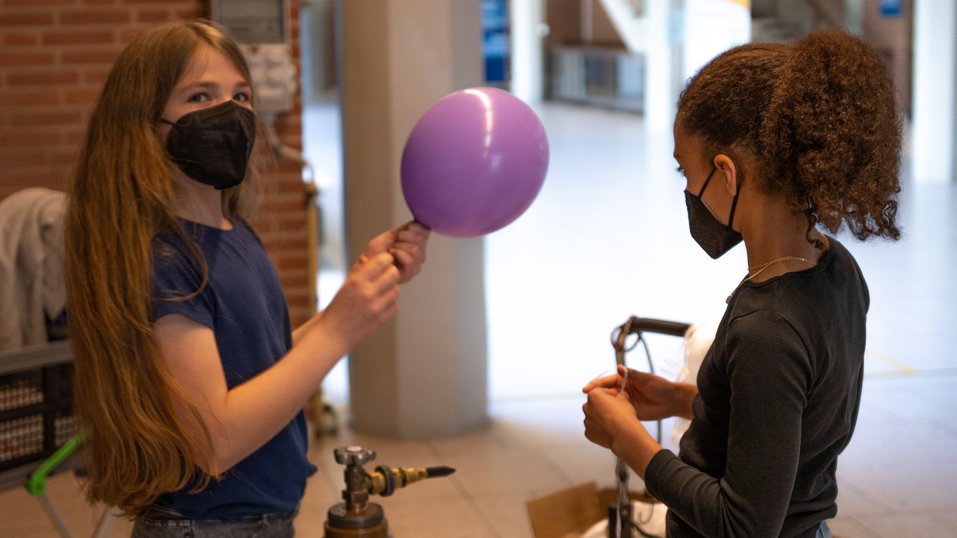 Die Mädchen befüllen die Ballons mithilfe einer Gasflasche.