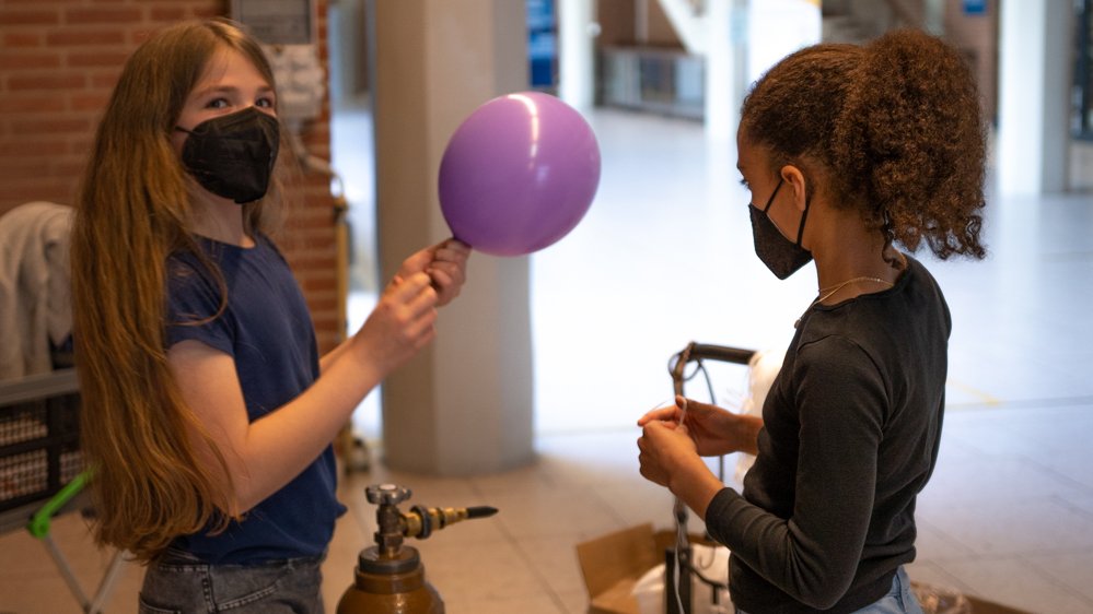 Die Mädchen befüllen die Ballons mithilfe einer Gasflasche.