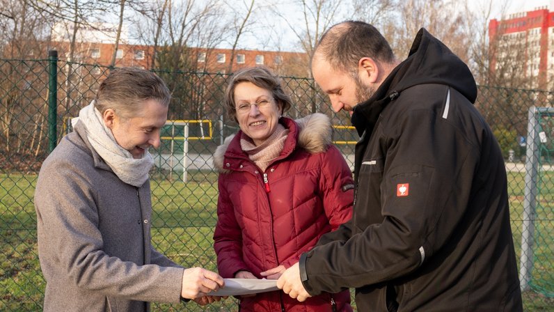 Drei Personen gucken gemeinsam auf einen Plan