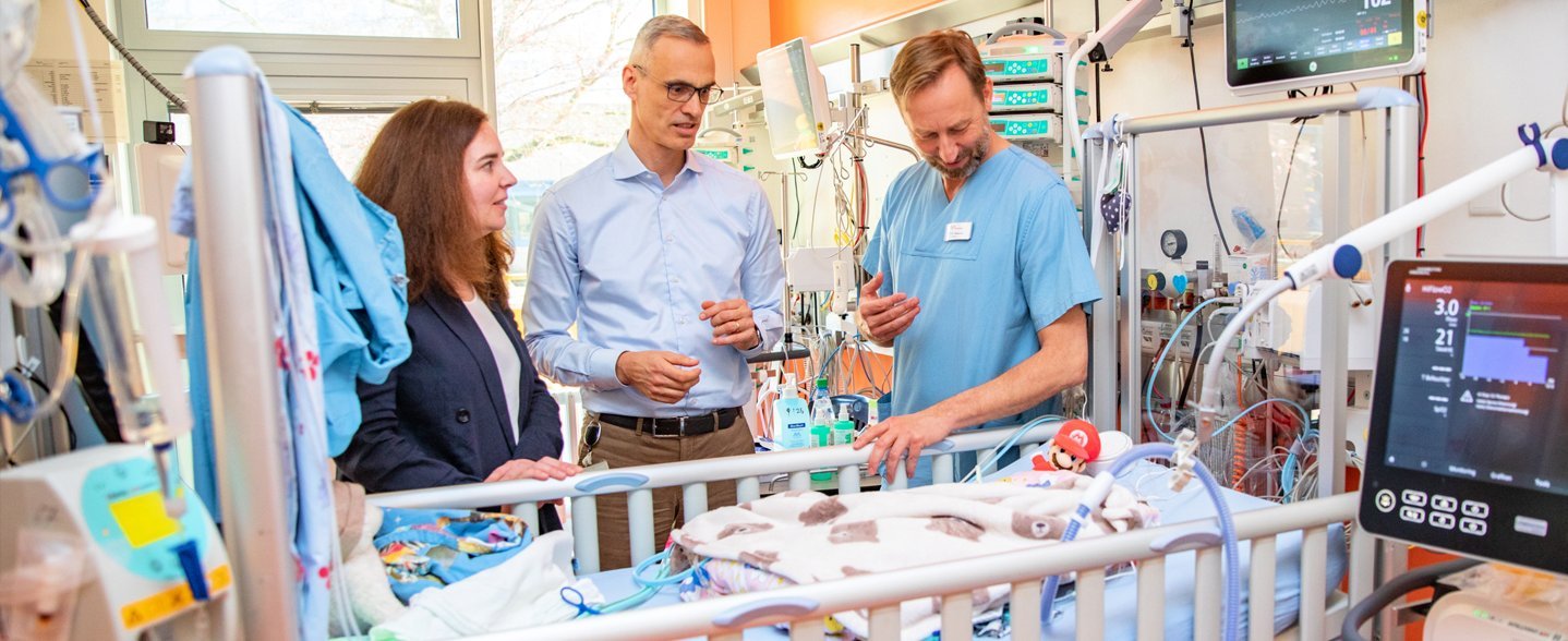 Professorin Dr. Helena U. Zacharias (PLRI), Dr. Bernd Auber (MHH-Institut für Humangenetik) und Privatdozent Dr. Thomas Jack stehen an einem Intensivbett für Neugeborene.
