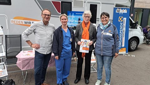 Elke Wiethake vom Klinikum Braunschweig mit einer Patientin, Nicole Drewes vom Klinikum Lüneburg und Dr. Frank Logemann von der MHH stehen vor einem der Wohnmobile, die auf Tour gehen. 