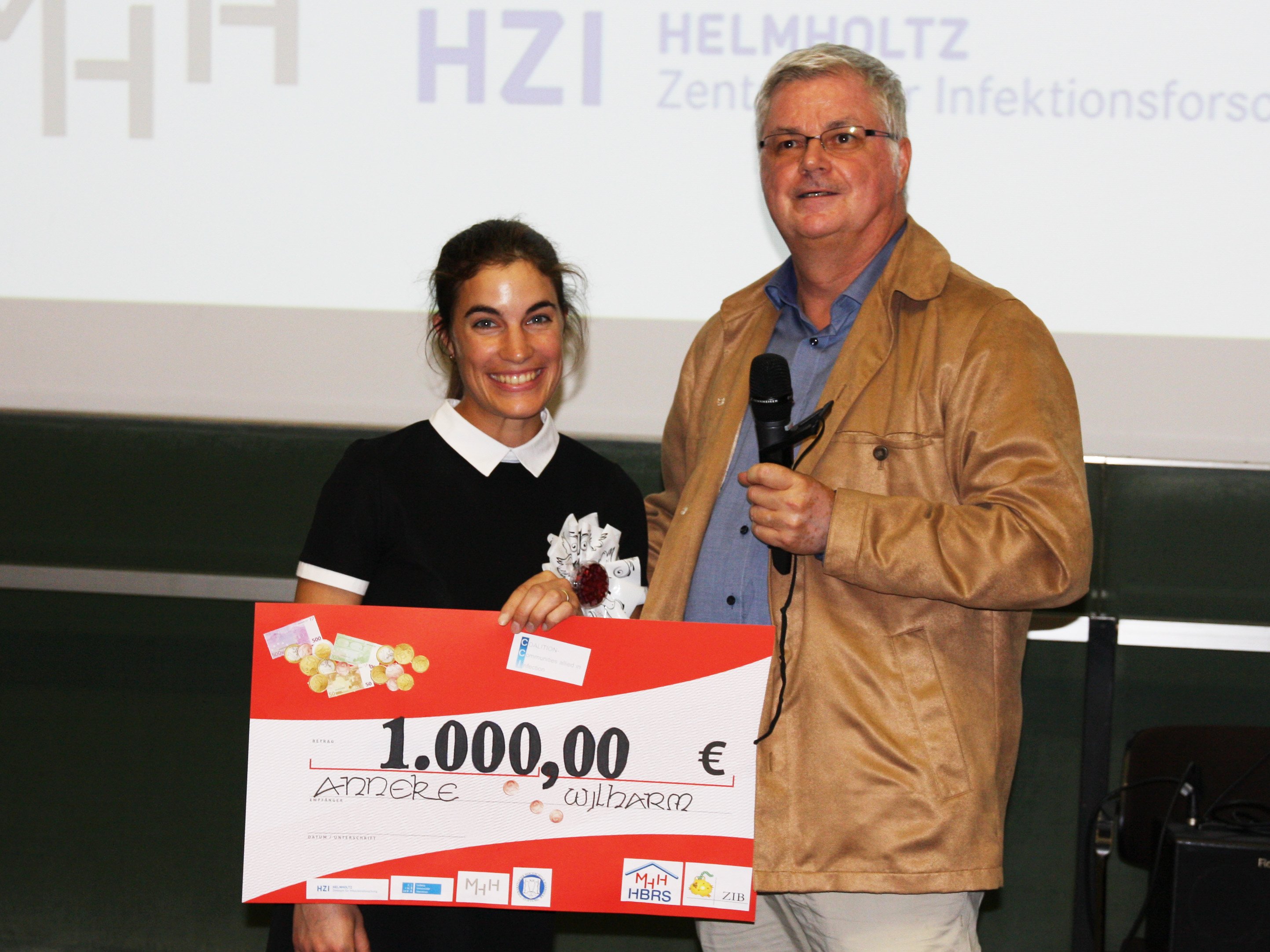 Copyright: Johann, Sabine/Institute of Immunology/MHH Vorstandsmitglied übergibt Doktorandin einen Scheck